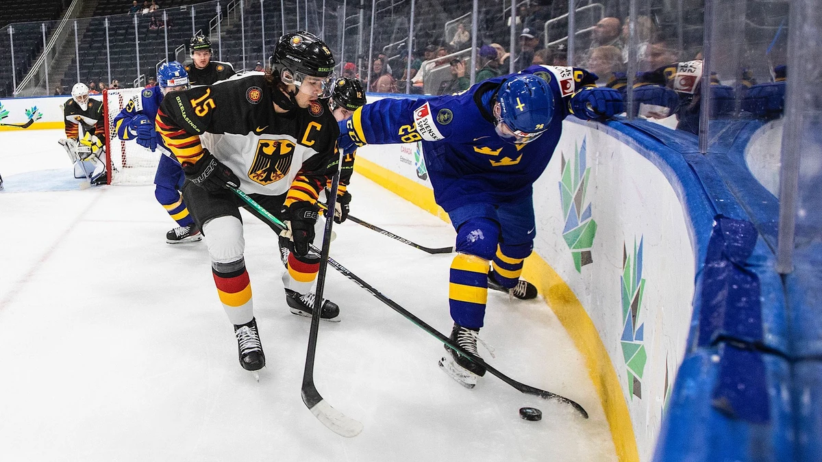 Sweden's Oskar Magnusson (28) and Germany's Luca Munzenberger (15) vie for the puck during the first period of an IIHF world junior hockey championships game Monday, Aug. 15, 2022, in Edmonton, Alberta. (Jason Franson/The Canadian Press via AP)