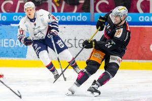 Eishockeyspieler Simon Bourque mit der Nummer 24 der Vienna Capitals im schwarzen Heimtrikot im Zweikampf gegen einen Spieler von Hydro Fehérvár AV19 in der STEFFL Arena Wien.