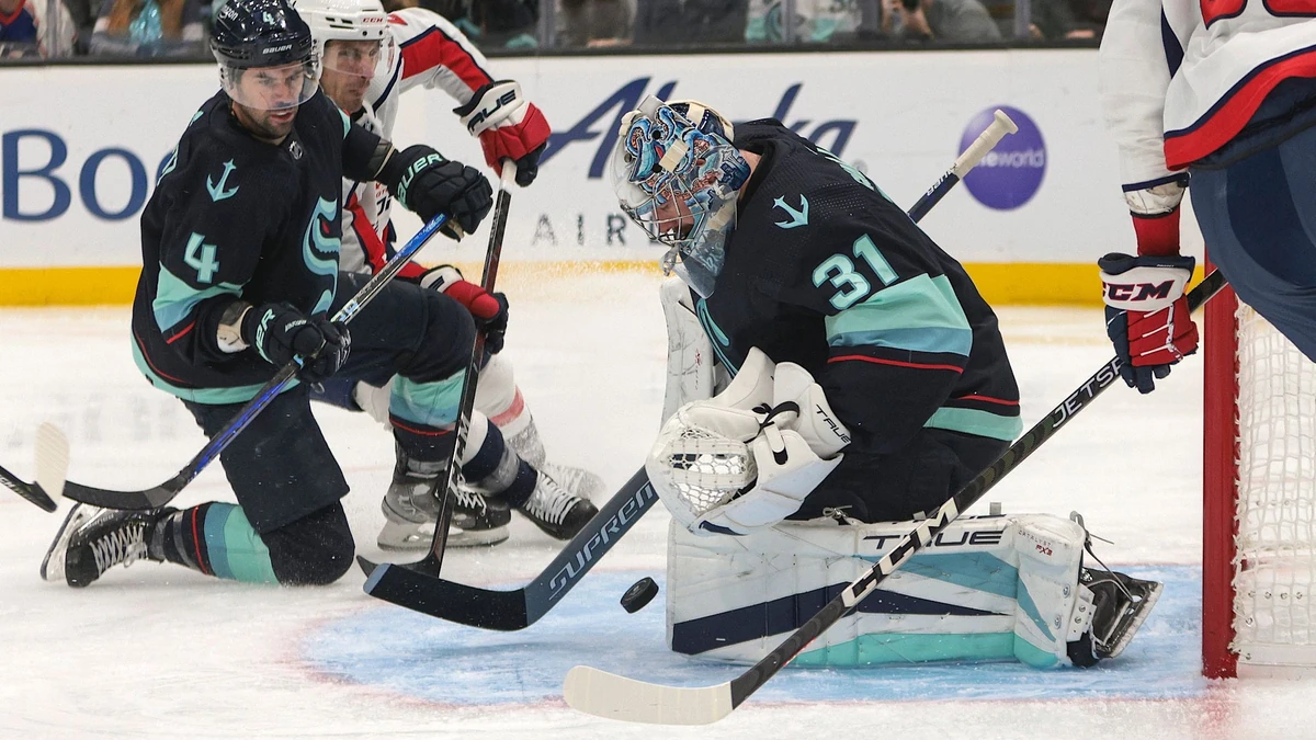 Seattle Kraken goaltender Philipp Grubauer (31) makes a save as defenseman Justin Schultz (4) blocks Washington Capitals right wing Garnet Hathaway during the third period of an NHL hockey game Thursday, Dec. 1, 2022, in Seattle. The Kraken won 3-2. (AP Photo/Jason Redmond)