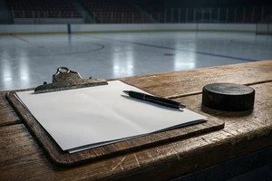 Eishockey-Vertrag und Puck auf der Trainerbank: Symbolbild für Transfers und Vertragsverlängerungen – Hockeyweb.de