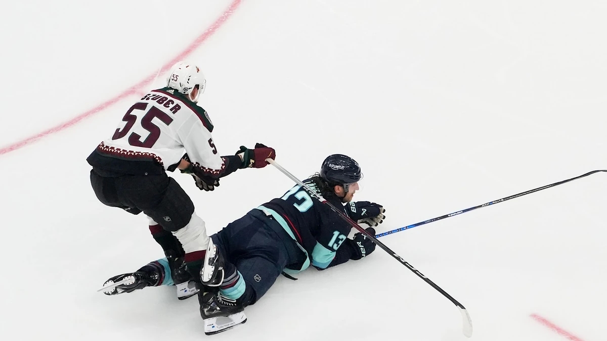 Seattle Kraken left wing Brandon Tanev (13) collides with Arizona Coyotes defenseman Maksymilian Szuber (55) as goaltender Karel Vejmelka (70) looks on near the goal during the first period of an NHL hockey game Tuesday, April 9, 2024, in Seattle. (AP Photo/Lindsey Wasson)